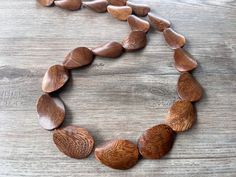 One long strand of dark brown wood beads with brown glass spacer beads.  - Length is 38"  (can vary depending on the beads)  - Beads measure 1.5" by 1" - Lead free pewter toggle (gold toggle and stainless steel clasp also available)  The necklace length can be customized. The mannequin's neck size is 14.5".  If you would like a multi strand version or other colors: www.etsy.com/shop/DanaLeBlancDesigns?ref=seller-platform-mcnav&search_query=miranda+wood  We use the highest quality findings to ens Adjustable Single Strand Brown Beads, Artisan Brown Spacer Beads, Adjustable Brown Beaded Necklaces With Oval Beads, Adjustable Brown Oval Beads, Earthy Polished Brown Beads, Earthy Brown Polished Beads, Artisan Brown Beaded Necklaces With Oval Beads, Brown Wooden Beads For Jewelry Making, Artisan Brown Beaded Necklace With Oval Beads