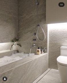 a white toilet sitting in a bathroom next to a bath tub filled with foams