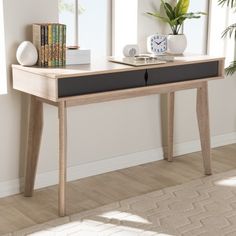 a wooden table with two drawers on it in front of a window and a potted plant