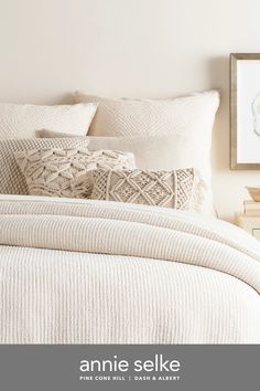 a white bed topped with pillows and blankets