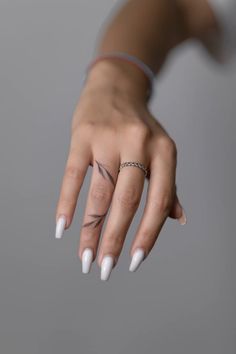 a woman's hand with white nails and a ring