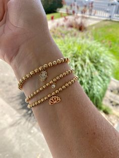 14K gold filled beaded stretch bracelets with 18K gold filled charms- classic and minimalist. Perfect for stacking and layering. Comfortable and light weight to wear. They are rust and tarnish resistant. Made with 14K gold filled beads in 3, 4 and 5mm. You can wear these as a single or add and create your stack. Each can be worn casually or dressed up. Choose your bead size 3, 4 and 5 mm and either choose to leave it plain or from one of three beautiful and elegant charms. Charm choices include: 4mm 18K gold micro pave cubic zirconia (cz) circle pendant, 18K gold filled lotus pendant and 18K gold filled CZ micro pave Hamsa evil eye charm. All bracelets are lead free, nickel free and hypoallergenic.  All bracelets are made to order and available in four sizes:  6 inches 6.5 inches 7 inches Gold Stretch Bracelet With Tiny Beads For Gift, Spiritual Gold Beaded Bracelets With Charms, Dainty Gold Stretch Bracelet With Gold Beads, Dainty Gold Bead Stretch Bracelet, Dainty 14k Gold-filled Stretch Bracelet With Gold Beads, Flexible Gold Bracelet With Tiny Beads, Gold Stretch Bracelet With Charms As Gift, Gold Stretch Bracelet With Charms For Gift, Minimalist Gold Stretch Bracelet With 8mm Beads