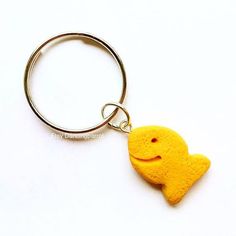 a yellow cookie shaped like a fish on a keychain with a smiley face