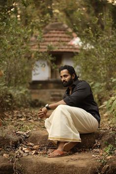 a man sitting on top of a stone step in the middle of some leaves and trees