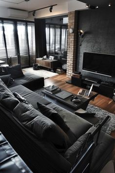 a living room filled with black furniture and a flat screen tv mounted on the wall