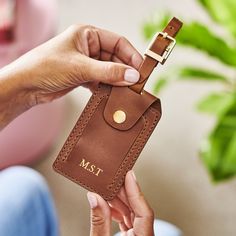 a person holding a brown leather card case with the initials ms and t on it