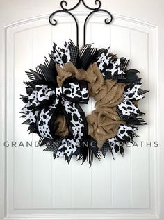 a black and white wreath hanging on the side of a door with an animal print bow