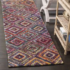 a multicolored rug on the floor next to a wicker chair and shelf