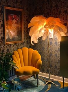 an orange chair with feathers on it in front of a wallpapered background and a lamp