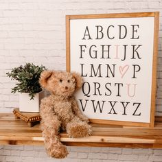 a teddy bear sitting on a shelf next to a sign