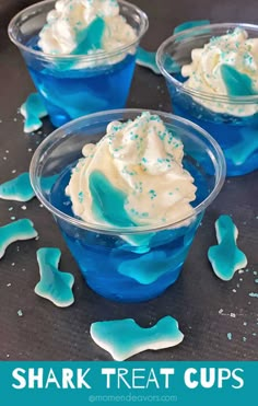 three small cups filled with blue jello and white frosting on top of a table