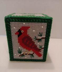 a green and white box with a red bird on it's side, sitting on a table