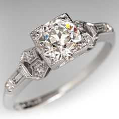 This lovely architectural circa 1920s Art Deco ring is centered with one (1) old European cut diamond, weighing 0.95 carats, that is prong set in a square frame with milgrain edging. Each shoulder is accented with three (3) bead set round single cut diamonds, and one (1) bezel set baguette cut diamond. The shoulders also have milgrain edges. The ring measures 6.2mm at the top, rises 6.1mm above the finger, tapering to 1.3mm wide and 1.0mm thick at the base of the shank.  The ring is crafted in platinum and is currently a size 5.  One of the baguette diamonds has a tiny corner chip that cannot be seen while worn. Luxury Art Deco Diamond Ring With Vvs Clarity, Luxury Art Deco Diamond Ring With Prong Setting, Luxury Diamond White Sapphire Art Deco Ring, Luxury Art Deco Ring With Polished Finish, Luxury Art Deco Princess Cut Diamond Ring, Luxury Vintage Baguette Cut Diamond Ring, Luxury Art Deco Princess Cut Jewelry, Luxury Art Deco Diamond Ring With Polished Finish, Luxury Single Diamond Art Deco Ring