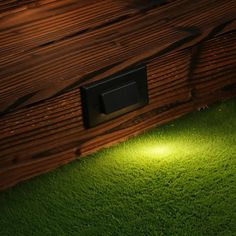 a wooden box with a light on it in the grass next to a door way