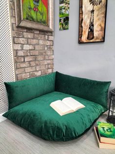 a green bean bag chair with an open book on it in front of a brick wall