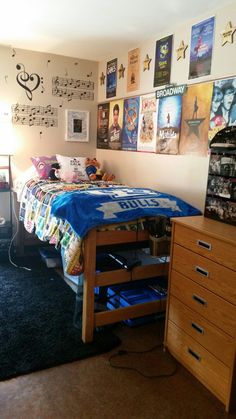 a bed room with a neatly made bed and lots of posters on the wall