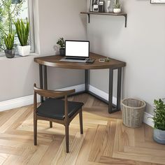 a laptop computer sitting on top of a wooden desk next to a potted plant