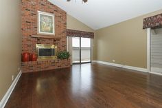 an empty living room with hard wood floors and brick fireplace in the center, along with sliding glass doors