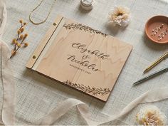 a wooden wedding guest book on a table with flowers and other items to decorate it