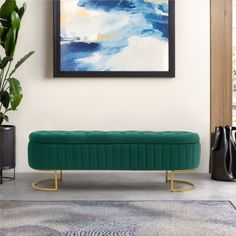 a green velvet bench in front of a painting and potted plant on the floor