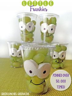 an image of some green apples in plastic cups with googly eyes on them for halloween