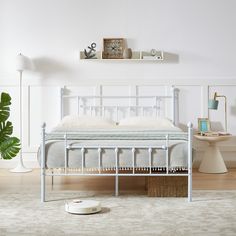 a white bed sitting on top of a wooden floor next to a wall mounted clock