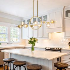 a kitchen with white cabinets and an island in the middle is lit by pendant lights