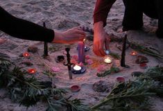 two people kneeling in the sand with candles