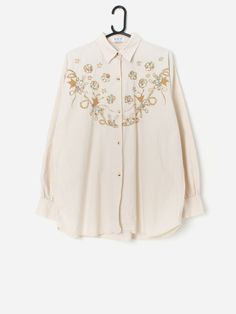 Vintage embroidered appliqué blouse with pretty floral design. This pretty beige blouse has golden brown and multicoloured flowers embroidered onto the front to create a truly beautiful piece! This blouse also features a full length button closure and buttoned cuffs. Made from a lightweight soft cotton.  Our recommended size: Large Label says: No size label Condition: Very good Material: 100% cotton Measurements in inches: Pit to pit: 23.5 Shoulders: 20.5 Front length: 30 Back length: 30.5 Sleeve length:23 Hem: 23 We recommend that you compare our measurements to a similar item of your own to ensure good fit. Measurements are taken flat and doubled for waist and hip. Our items are vintage and may show signs of previous wear, etc. Any significant wear, damage or obvious marks will be photog Cotton Button-up Blouse With Floral Embroidery, Fall Floral Print Blouse With Multicolor Embroidery, Elegant Long Sleeve Tops With Floral Applique, Summer Embroidered Beige Blouse, Fall Blouse With Multicolor Floral Embroidery, Elegant Long Sleeve Blouse With Floral Applique, Summer Beige Blouse With Floral Embroidery, Embroidered Beige Blouse For Summer, Beige Blouse With Floral Embroidery For Summer