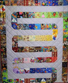 a quilt made to look like the letter e with many different colors and designs on it