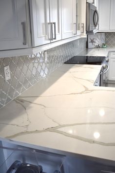 a kitchen with white cabinets and marble counter tops