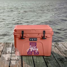 an orange yeti cooler sitting on top of a wooden dock next to the ocean