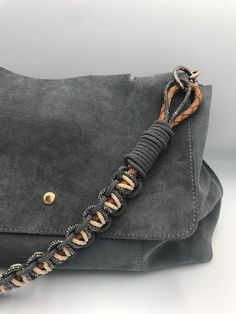 a gray suede handbag with braided handles and gold hardwares on the front