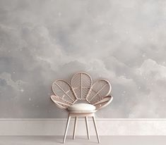 a white chair sitting in front of a wall with clouds painted on the wall behind it