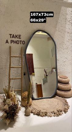 a large mirror sitting on top of a table next to a pile of pillows and vases