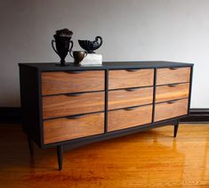 a black and brown dresser sitting on top of a hard wood floor