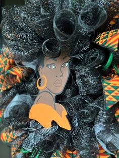 a woman's face is on the front of a black mesh wreath with orange and green ribbons