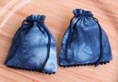 two small blue pouches sitting on top of a wooden table next to each other