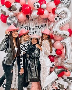 three girls posing in front of a balloon wall with the number two on it and balloons all around them