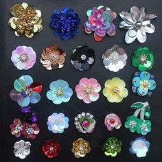 there are many different colored flowers on the black table together, and one has a flower brooch in it's center