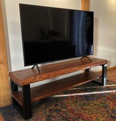 a flat screen tv sitting on top of a wooden stand in front of a wall