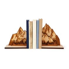 two bookends made out of wood with mountains in the background and trees on them