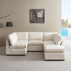 a living room with a large white sectional couch and lamp on the wall next to it