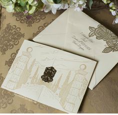 two envelopes are sitting next to each other on a table with flowers in the background