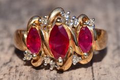 The Sullana Vintage Lab Grown Ruby and Diamond Ring. The ring Features three central rubies in a unique vintage patterned top with round diamonds set opposite each other on the ends. The ring is crafted in yellow gold and is a finger size 7 yet could be adjusted to any size. Each piece has been hand selected and meticulously identified and graded by a Graduate Gemologist who has been awarded a degree by the Gemological Institute of America (GIA). Please visit our Shop's About Page or our website Luxury Red Three Stone Jewelry, Luxury Red Three-stone Jewelry, Elegant Three-stone Red Diamond Ring, Elegant Three Stone Red Diamond Ring, Elegant Red Three-stone Diamond Ring, Elegant Red Three Stone Diamond Ring, Luxury Gold Ruby Three Stone Ring, Luxury Gold Three-stone Ruby Ring, Luxury Gold Three Stone Ruby Ring