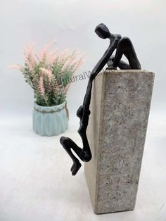 a statue sitting on top of a cement block next to a potted plant