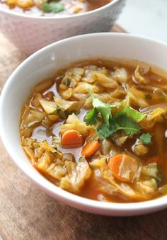 two bowls filled with soup on top of a wooden table