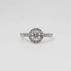 a white gold engagement ring with an oval diamond center and pave set diamonds around the band