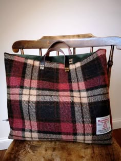 a plaid bag sitting on top of a wooden chair next to a coat hanger