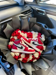 a pair of red sneakers sitting on top of a bouquet of roses in the back seat of a car